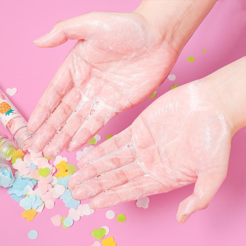 Soapy hands washing with colorful confetti and a bottle on pink background, skincare hygiene